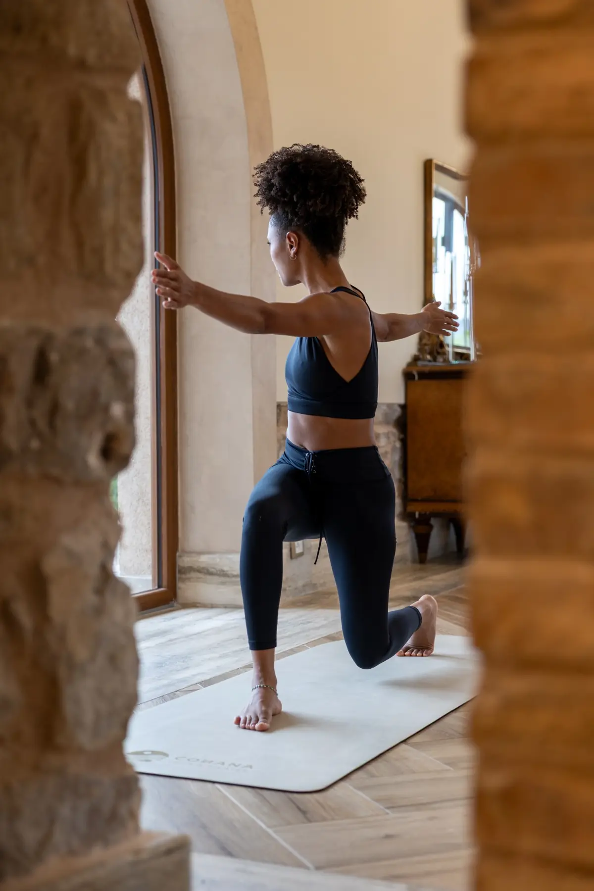 Ana in affondo basso, braccia aperte, interno con arco e finestra